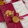 Close-up of burgundy gatefold card with gold foil wreath and cream insert