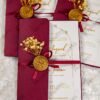 Burgundy satin ribbon and gold wax seal detail on gatefold invitation